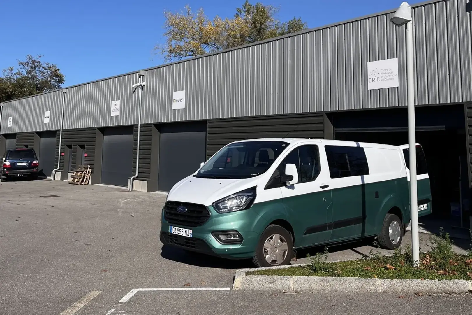 photo d'un van aménagé bleu et bleu canard garé au soleil